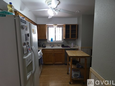 A kitchen with a white refrigerator and wooden cabinets.