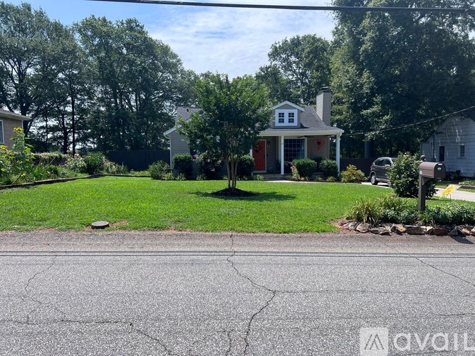 A house with a red door is surrounded by greenery.