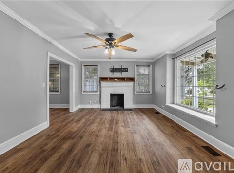 A spacious living room with a fireplace and wood flooring.