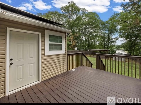 A deck with a white door and a window is surrounded by trees.