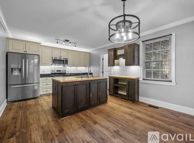 A modern kitchen with wooden floors and stainless steel appliances.