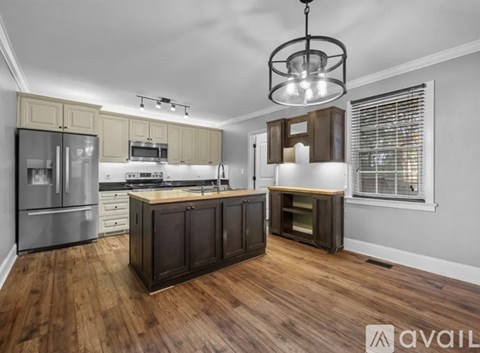 A modern kitchen with wooden floors and stainless steel appliances.
