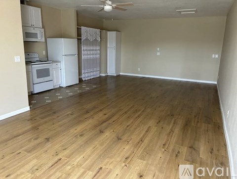 A kitchen with white appliances and wooden floors.