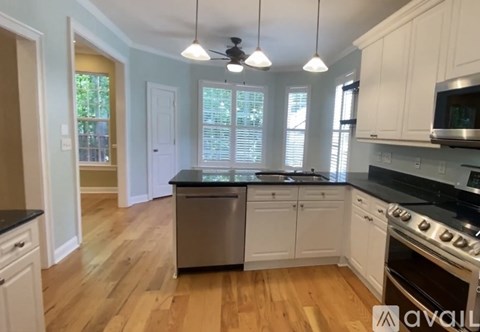 A kitchen with white cabinets and a wooden floor.