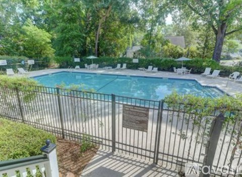 A pool surrounded by a fence and trees.