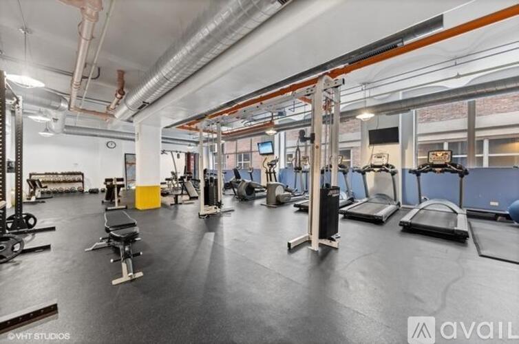 A gym with various exercise equipment and a TV mounted on the wall.