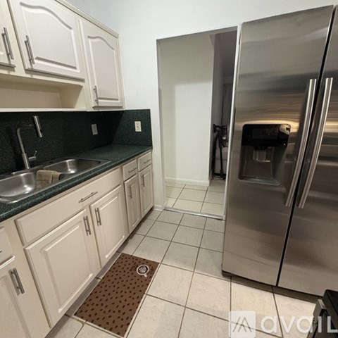 A kitchen with a stainless steel refrigerator and white cabinets.