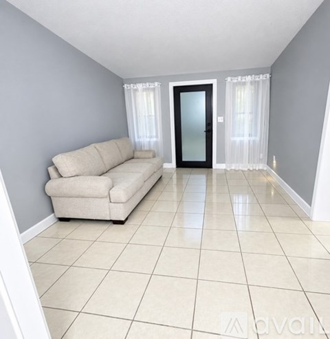 A spacious living room with a beige sofa and a black door.