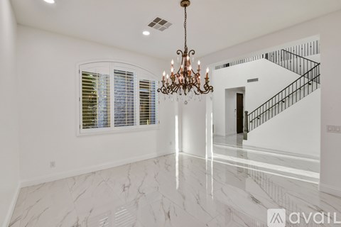 A chandelier hangs over a marble floor in a spacious room.