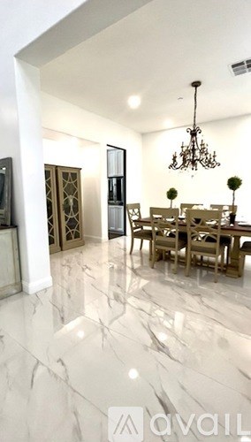 A dining room with a chandelier and a table set for six.