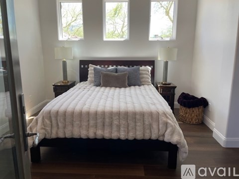 A bedroom with a large bed and two lamps.
