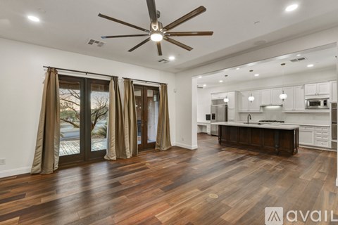 A spacious kitchen and living room with wood flooring and a ceiling fan.