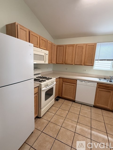 A kitchen with white appliances and wooden cabinets.