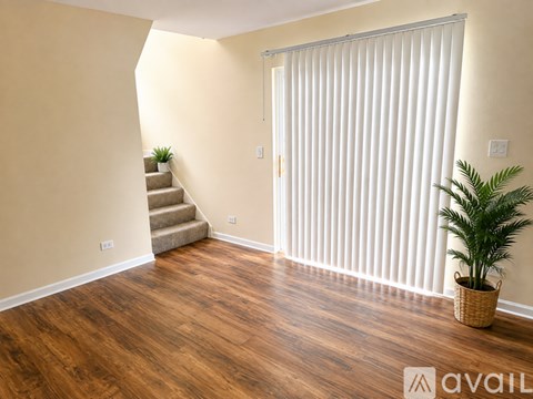 A room with wooden floors and a staircase leading to another room.