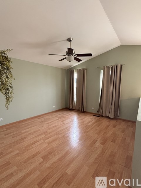 A room with wooden flooring and a ceiling fan.