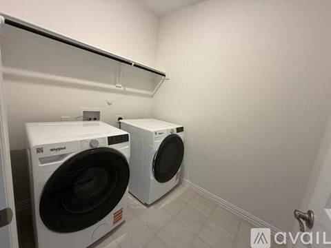 Two white Whirlpool washing machines in a laundry room.