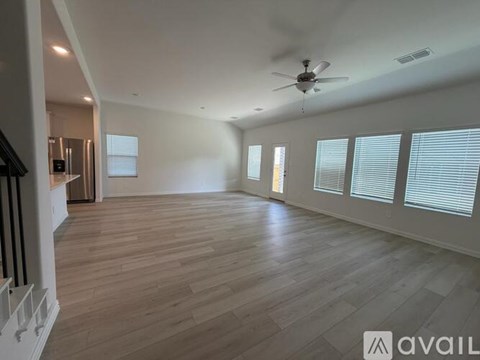 A spacious room with wooden flooring and a ceiling fan.
