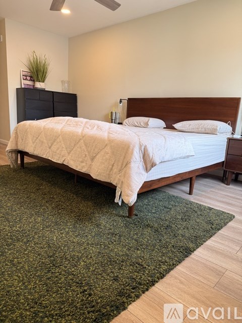 A bedroom with a bed, dresser, and ceiling fan.
