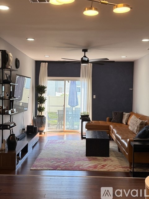 A living room with a brown leather couch and a wooden floor.