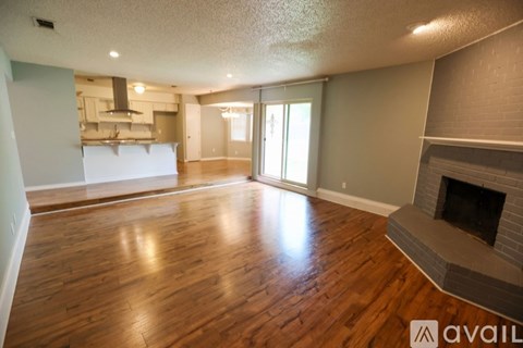 A spacious living room with wood flooring and a fireplace.