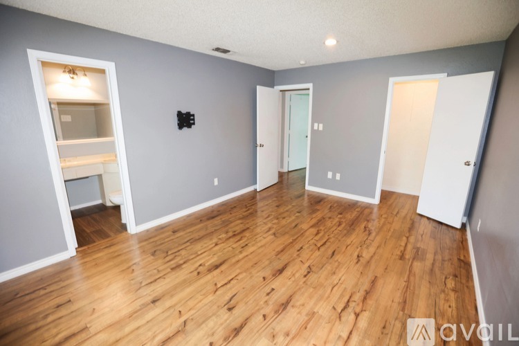 A spacious room with wooden flooring and white walls.
