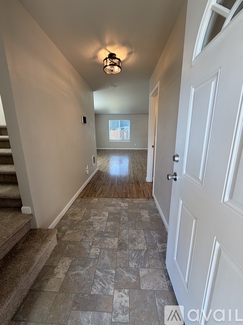 A hallway with a tiled floor and a white door.