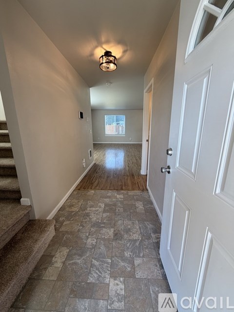 A hallway with a tiled floor and a white door.