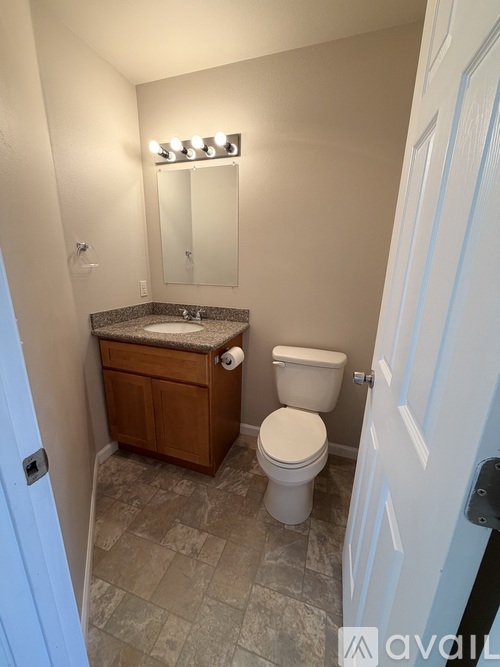 A bathroom with a toilet, sink, and mirror.