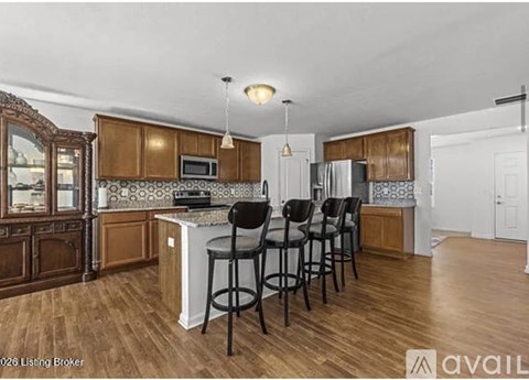 A kitchen with wooden cabinets and a white island with four black chairs.