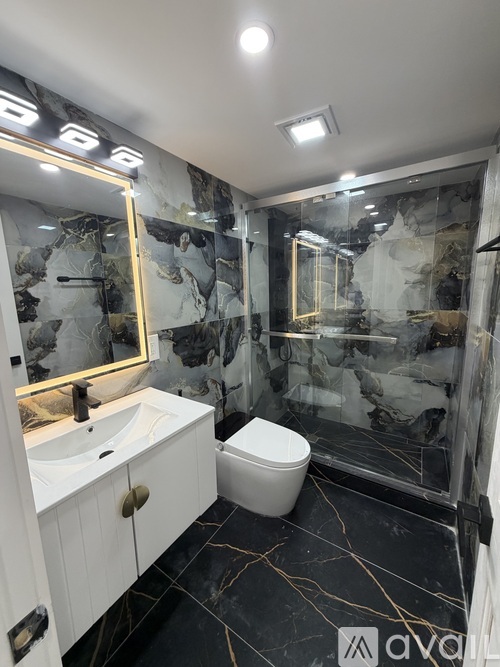 A bathroom with a marble patterned wall and a white toilet.