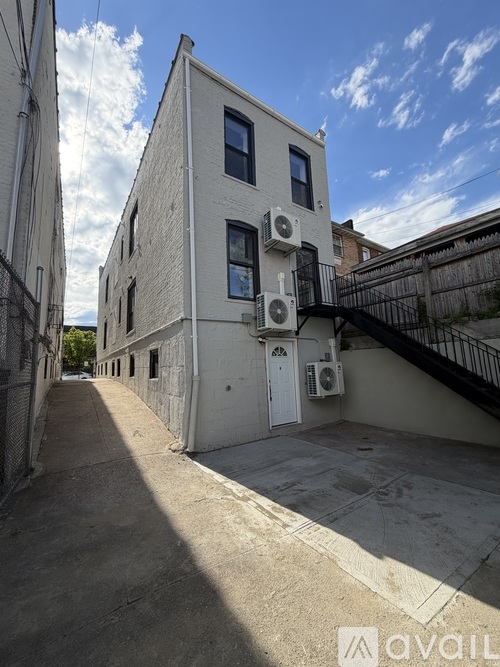 A narrow alley with a building on the right side and a fence on the left.