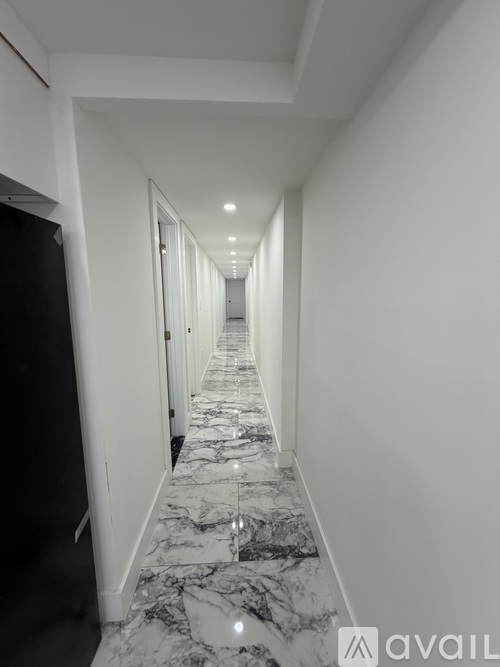 A long hallway with marble flooring and white walls.