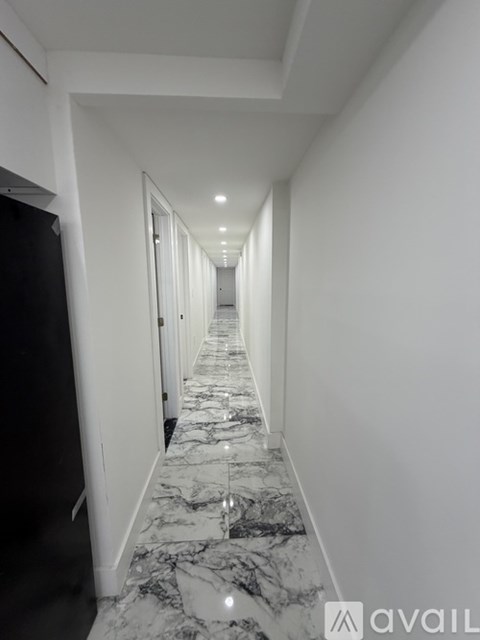 A long hallway with marble flooring and white walls.