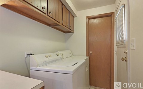 A white dishwasher is in a kitchen with wooden cabinets.