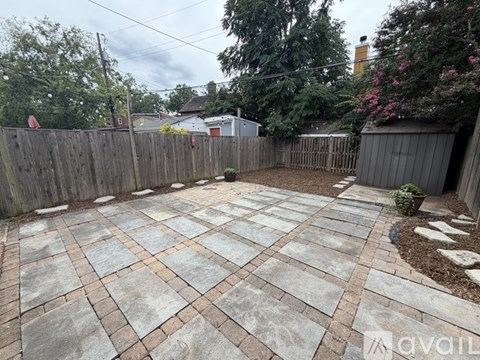 A backyard with a stone patio and a wooden fence.