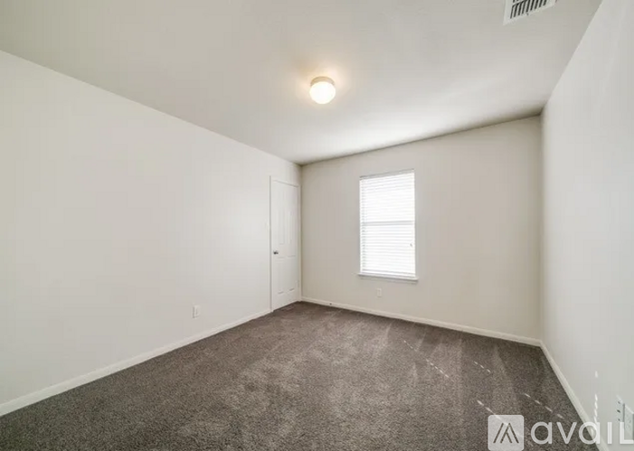 A room with a carpeted floor and a window with blinds.