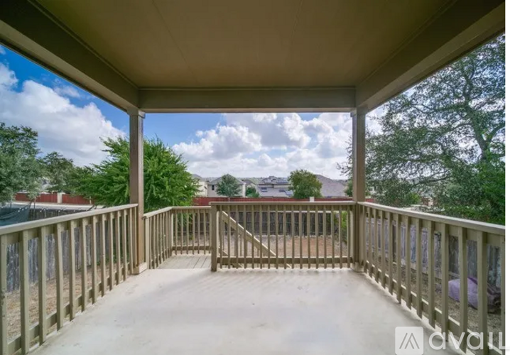 A wooden deck with a railing and a view of the sky and trees.