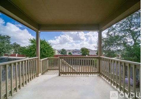 A wooden deck with a railing and a view of the sky and trees.