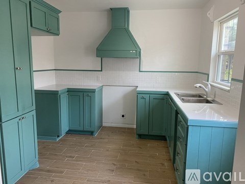 A kitchen with teal cabinets and a green range hood.