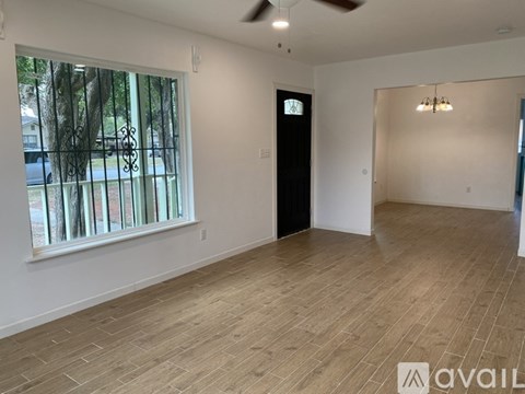 A room with wooden flooring and a window with a view of trees.