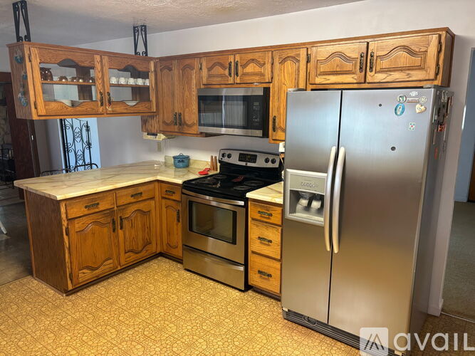 A kitchen with wooden cabinets and a stainless steel refrigerator.