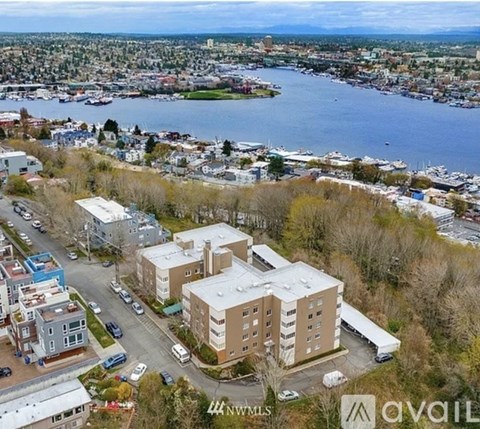 A bird's eye view of a city with a large building in the foreground and a body of water in the background.