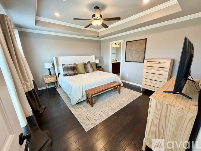 A bedroom with a bed, a television, and a ceiling fan.