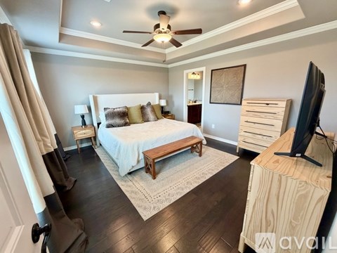 A bedroom with a bed, a television, and a ceiling fan.