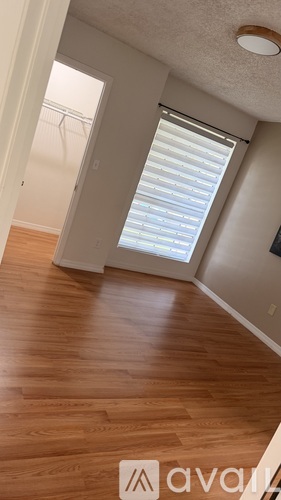 A room with wooden flooring and a window with blinds.