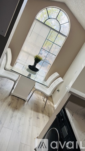A small potted plant sits on a table in front of a large window.