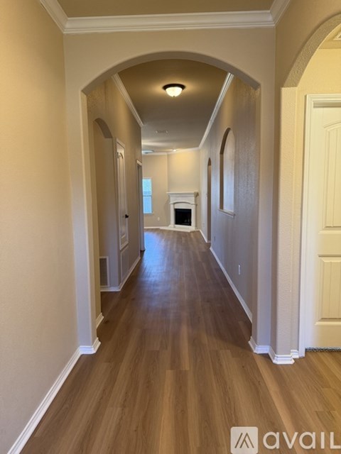 A long hallway with arched doorways and wood flooring.