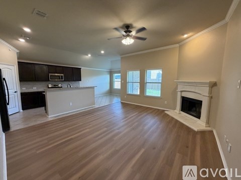 A spacious living room with a fireplace and a kitchen in the background.