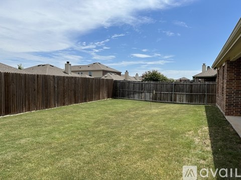 A backyard with a wooden fence and a grassy area.