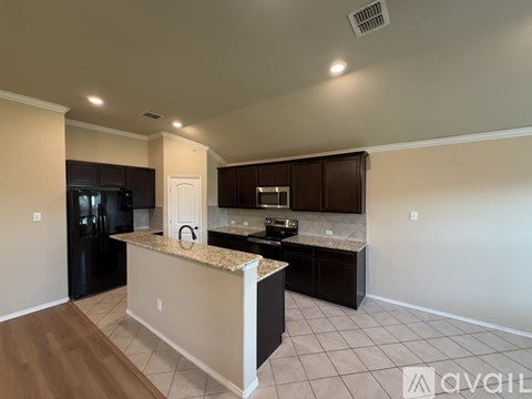 A kitchen with a granite countertop and dark cabinets.